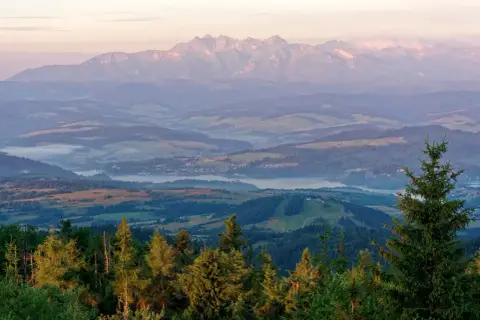 Widok z lubań szczyt na Tatry o wschodzie słońca. Mgły unoszą się nad doliną, a lasy i pola tworzą malowniczy krajobraz.