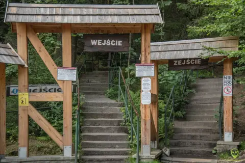 Kamienne schody prowadzą do wejścia na Szczeliniec Wielki. Drewniane bramy z tablicami informacyjnymi zapraszają do zwiedzania.