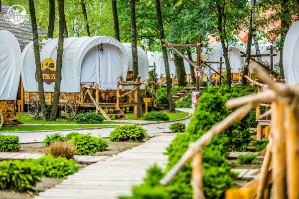 Wagony kempingowe w stylu western, idealne na wyjazd gdzie z dzieckiem w Krakowie. Drewniane ścieżki i bujna zieleń tworzą magiczny klimat.